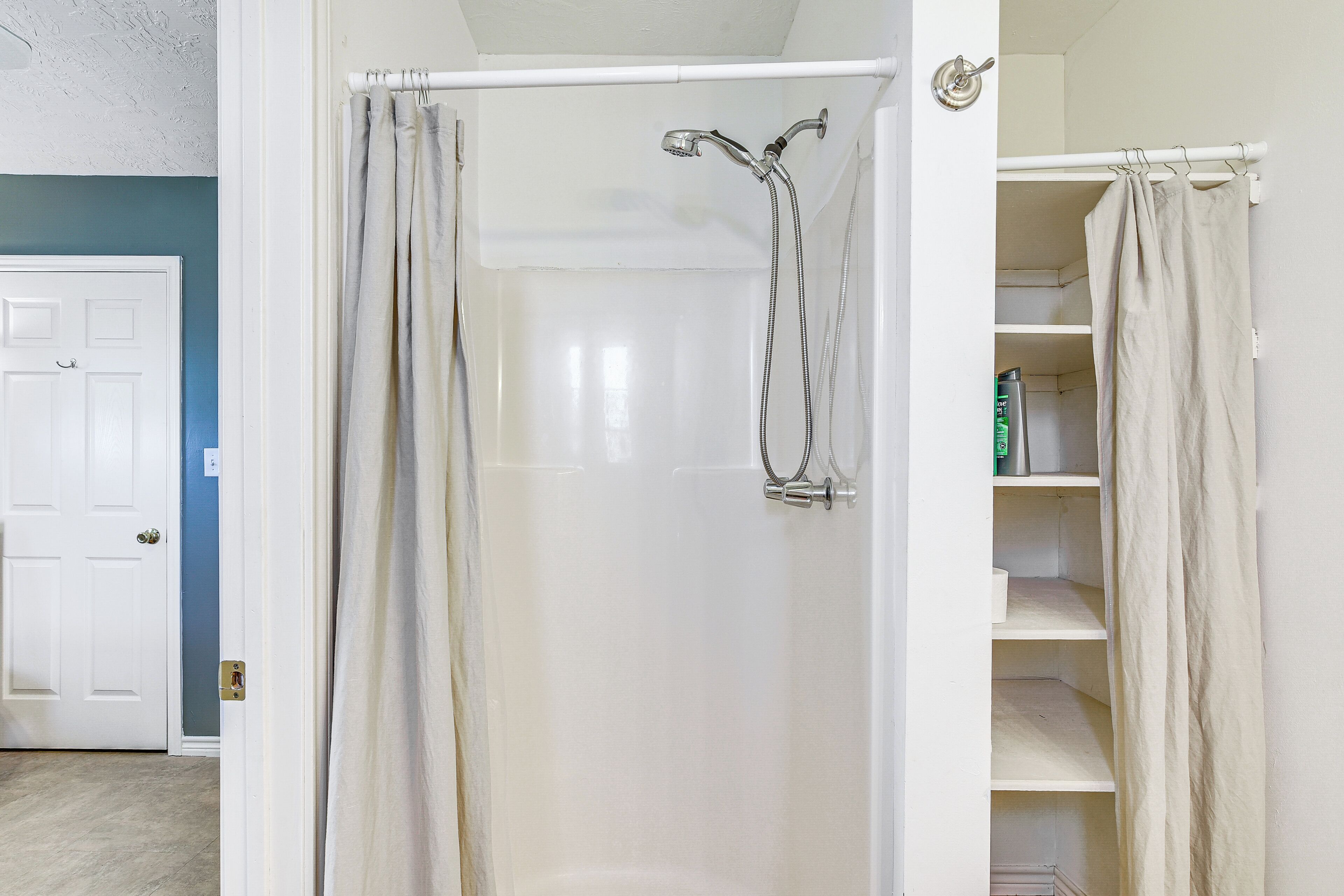 A walk-in shower with a glass door, a showerhead, and a towel rack.