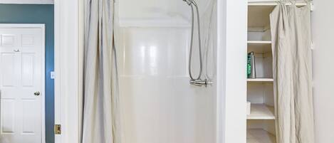 A walk-in shower with a glass door, a showerhead, and a towel rack.
