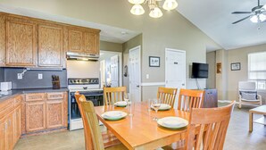 A spacious kitchen with wooden cabinets, a dining table set for four, and a ceiling fan. - Walk to Crystal Beach! Family & Pet-friendly Haven (Port Bolivar)