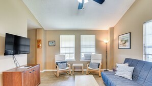 A living room with a wooden cabinet, two armchairs, a sofa, a ceiling fan, and a TV mounted on the wall. - Walk to Crystal Beach! Family & Pet-friendly Haven (Port Bolivar)