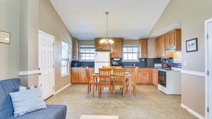 A spacious living room with a blue sofa and a dining area with wooden chairs and a table. - Walk to Crystal Beach! Family & Pet-friendly Haven (Port Bolivar)
