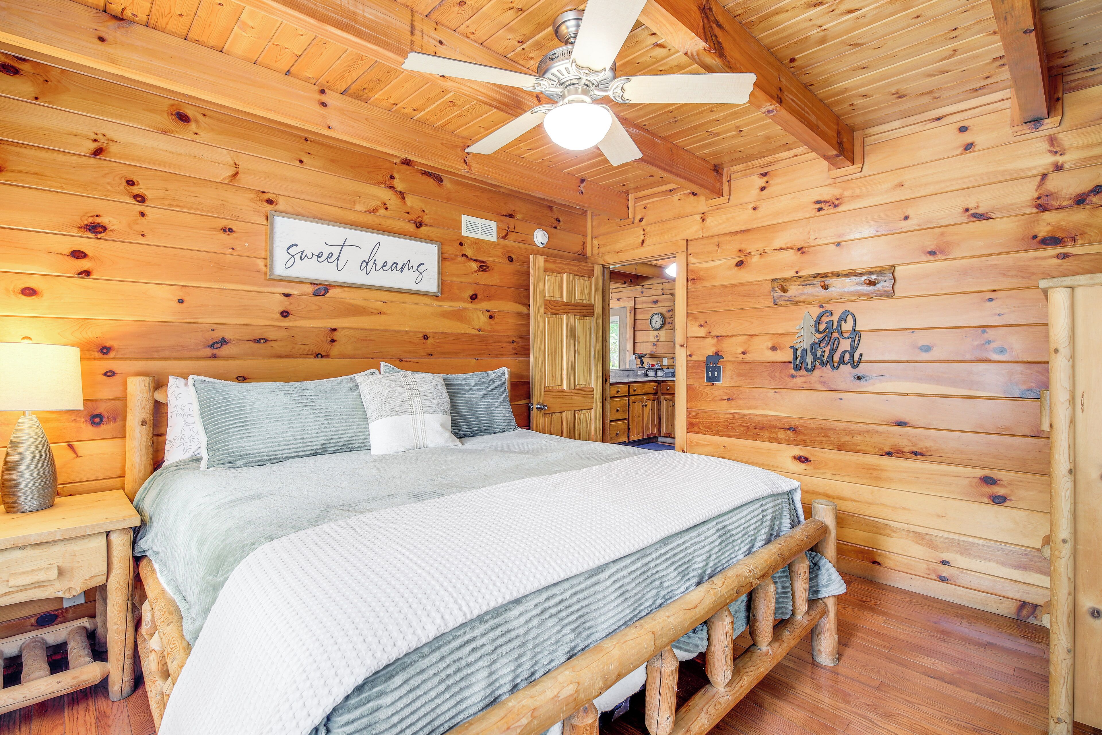 A wooden cabin bedroom with a bed, nightstands, a ceiling fan, and a sign that says "sweet dreams".