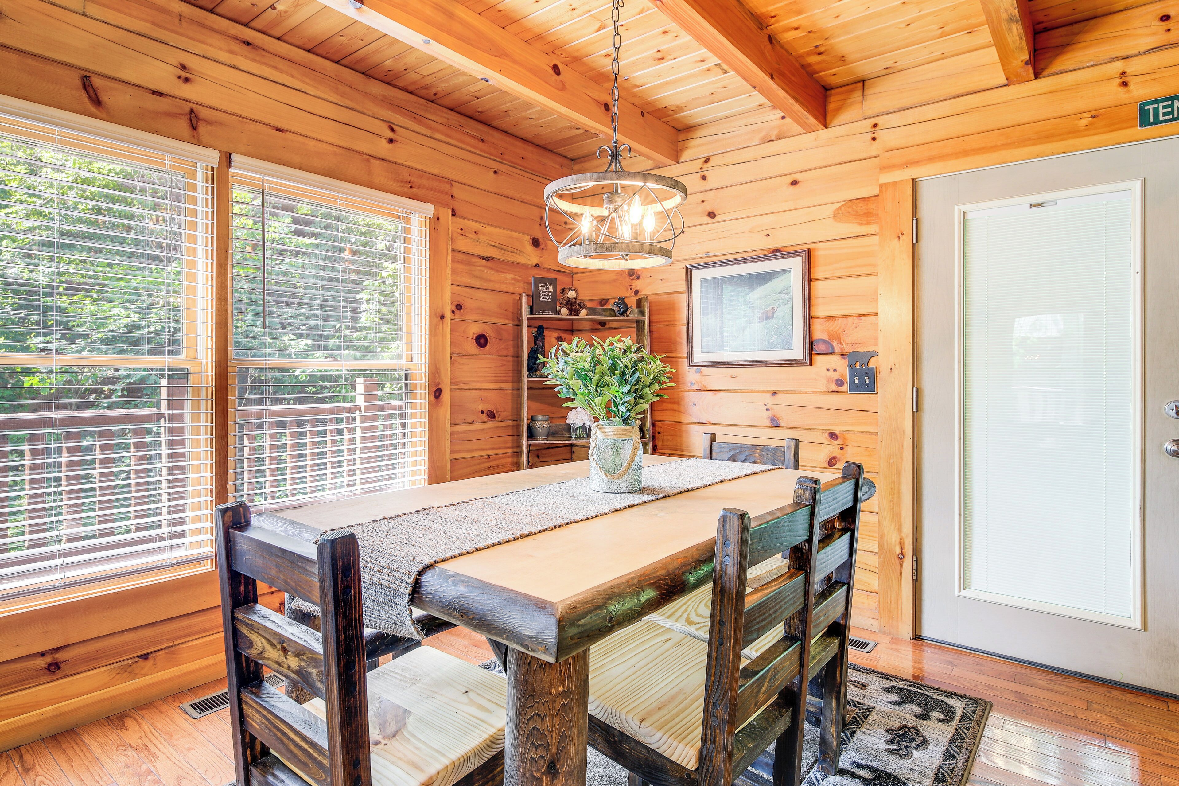A wooden interior with a dining table, chairs, a hanging light fixture, and a door labeled "TEN".