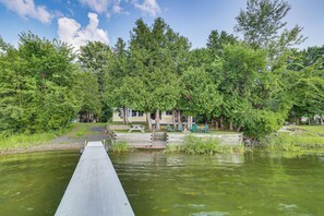 A wooden dock extending into a pond surrounded by lush greenery and trees. - Waterfront North Hero Home w/ Screened Porch (North Hero)