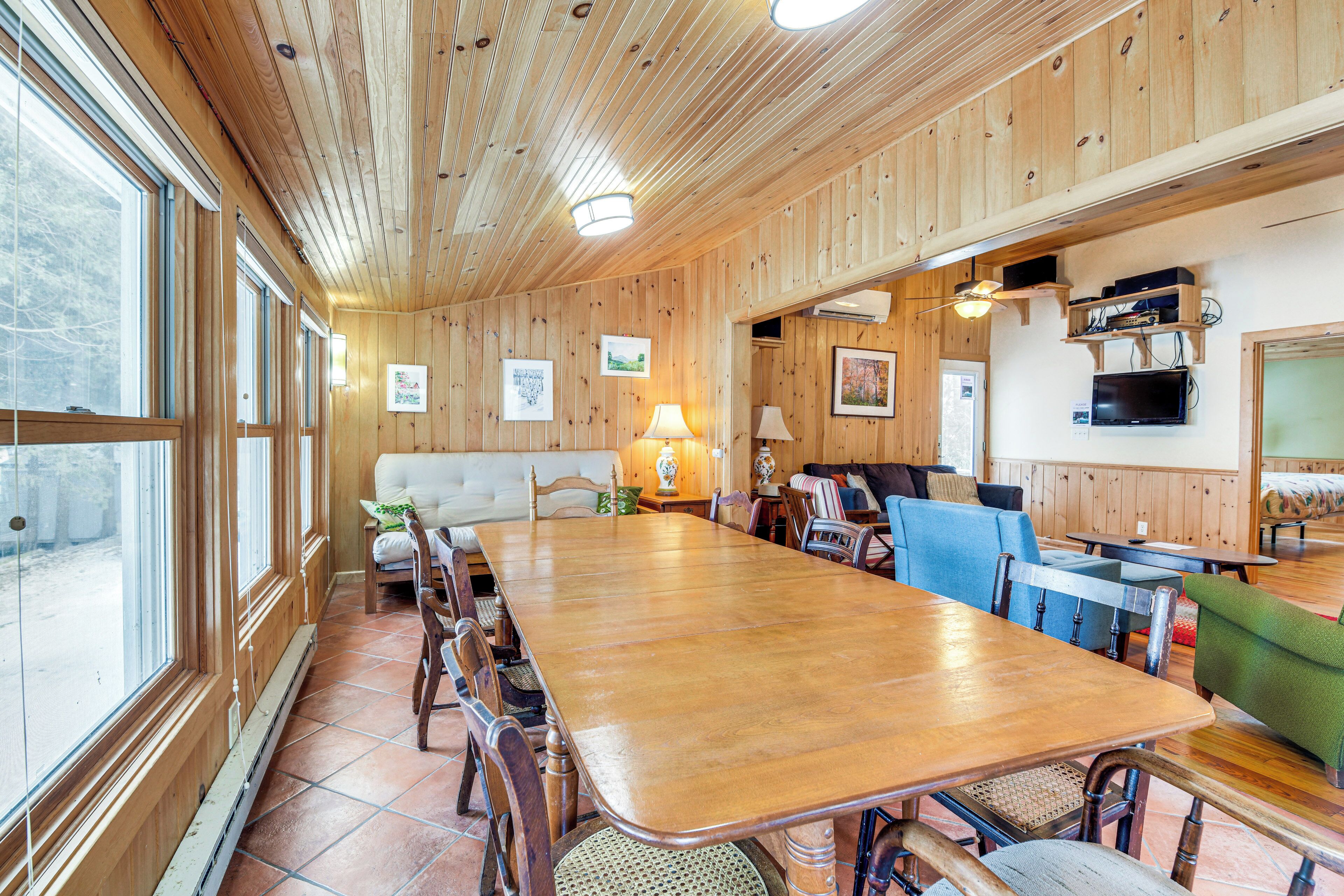 Un comedor amplio de madera con una mesa larga, sillas y un sofá.