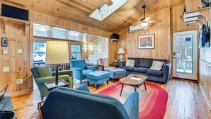 Een houten interieur met een bank, stoelen, een bijzettafeltje en een rode vloerkleed.