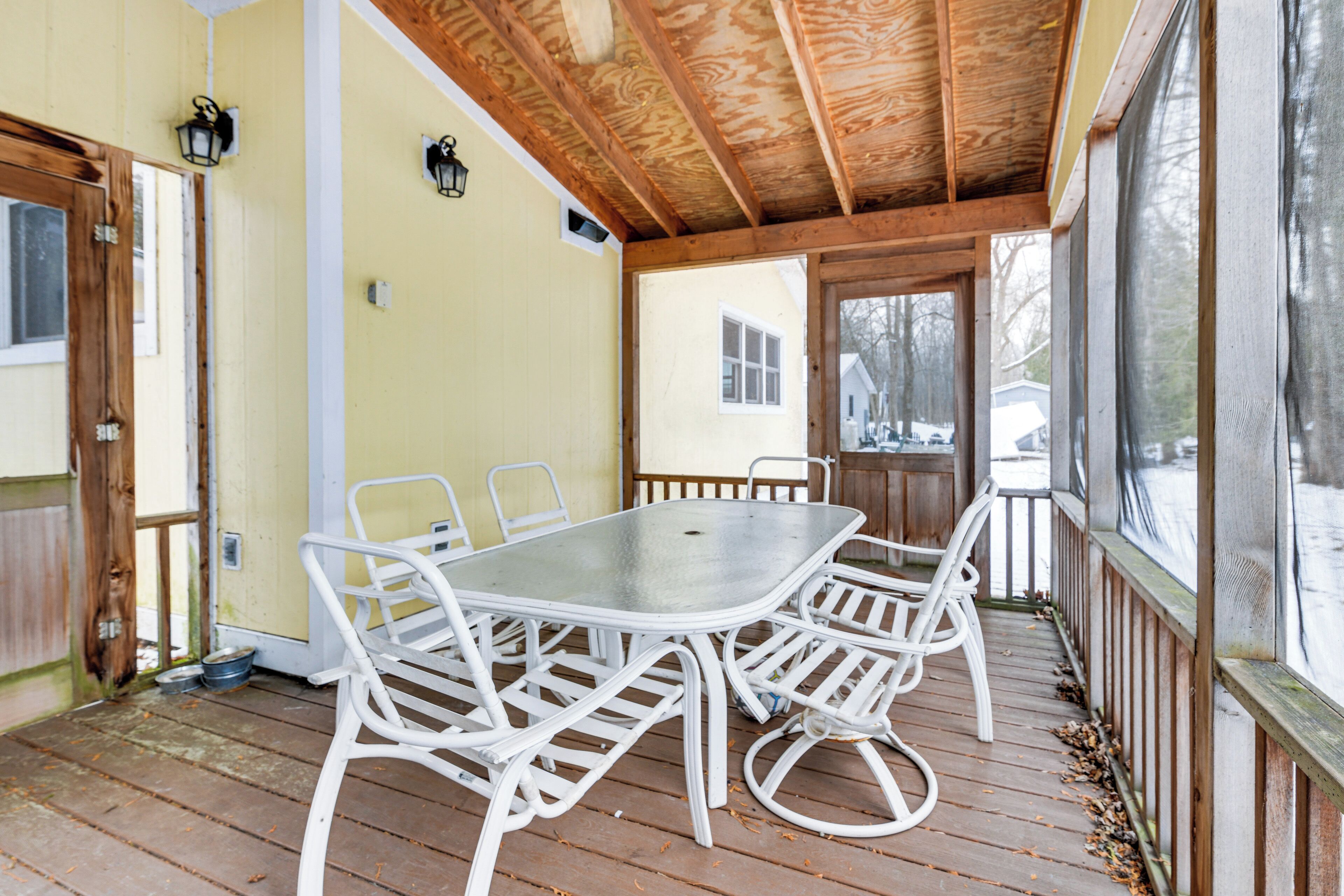 Une véranda avec une table et des chaises, des poutres en bois et une vue sur l ’extérieur.