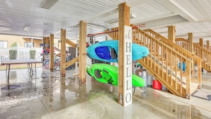 Un espacio al aire libre techado con una escalera de madera, kayaks y un letrero que dice 