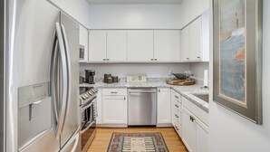 A modern kitchen with white cabinets, stainless steel appliances, and a marble countertop. - Walk to Lake Michigan - South Haven Condo! (South Haven)