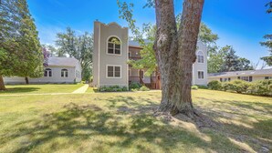 A residential building with a central tower, a front yard with a large tree, and a pathway leading to the entrance. - Walk to Lake Michigan - South Haven Condo! (South Haven)