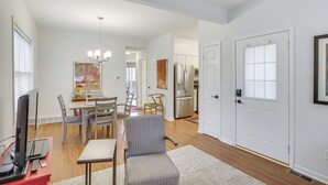 A spacious living area with a dining table, chairs, a TV, and a kitchen in the background. - Walk to Lake Michigan - South Haven Condo! (South Haven)