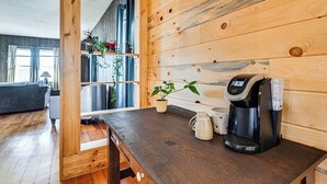A wooden interior with a coffee maker on a counter, a potted plant, and a view into another room with a couch and a window. - Lyndon Station Retreat ~ 9 Mi to Wisconsin Dells! (Lyndon Station)
