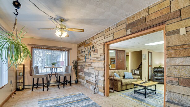 A spacious living area with a stone wall, a dining table with chairs, a sofa, and a coffee table. - Montour Falls Apartment ~ 3 Mi to Seneca Lake! (Montour Falls)