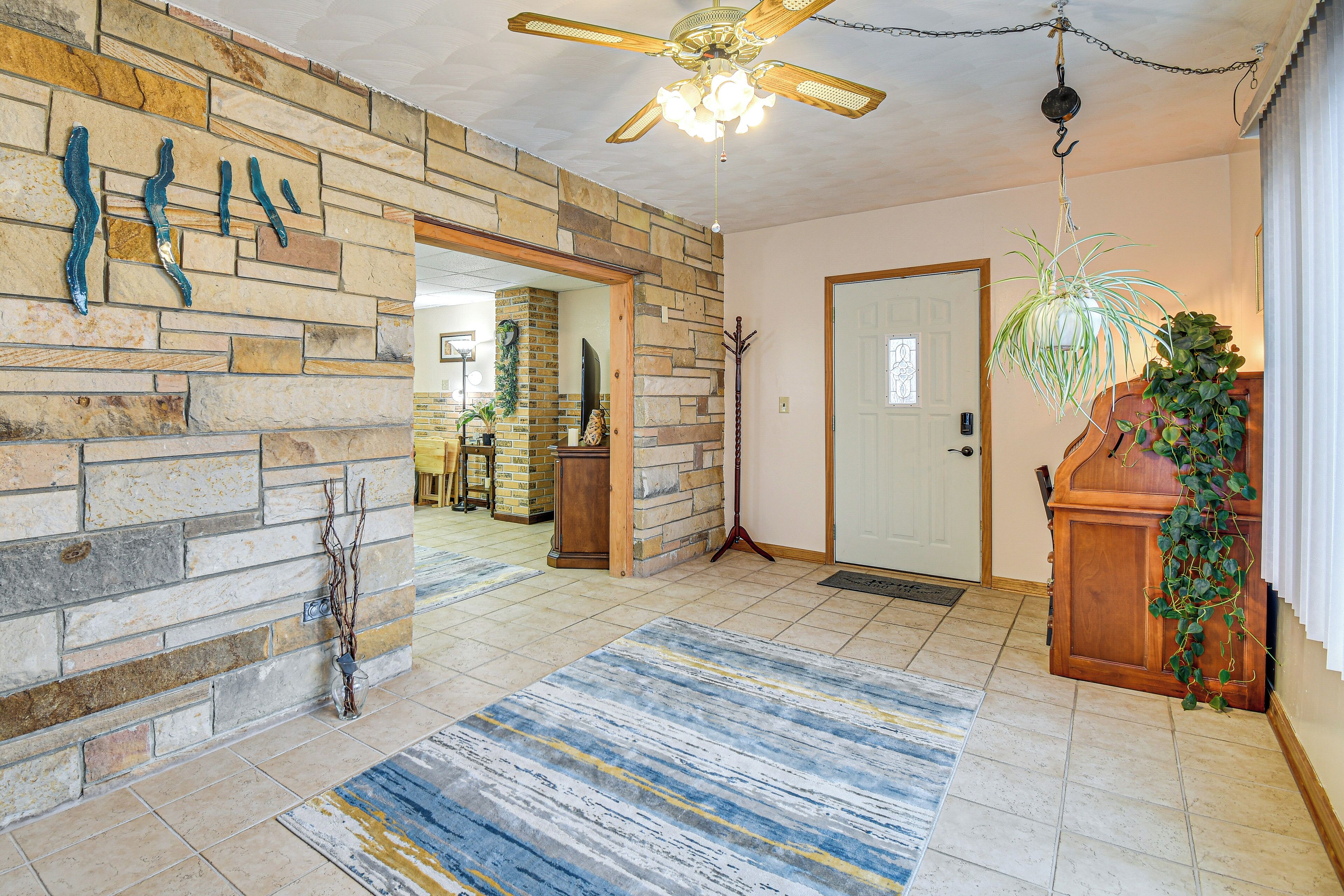 A spacious room with a stone wall, a wooden door, and a ceiling fan.