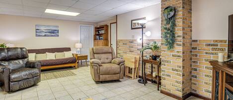 Ein Wohnzimmer mit Kamin aus Ziegelsteinen, Ledersofas und einem Bücherregal.