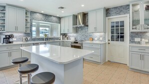 A modern kitchen with a central island, white cabinetry, and a backsplash with gray tiles. - Waterfront Palmetto Home w/ Private Pool & Dock! (Palmetto)
