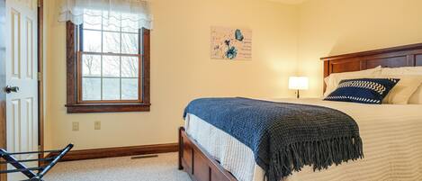 A bedroom with a bed, a window with a curtain, a wall-mounted artwork, and a door.