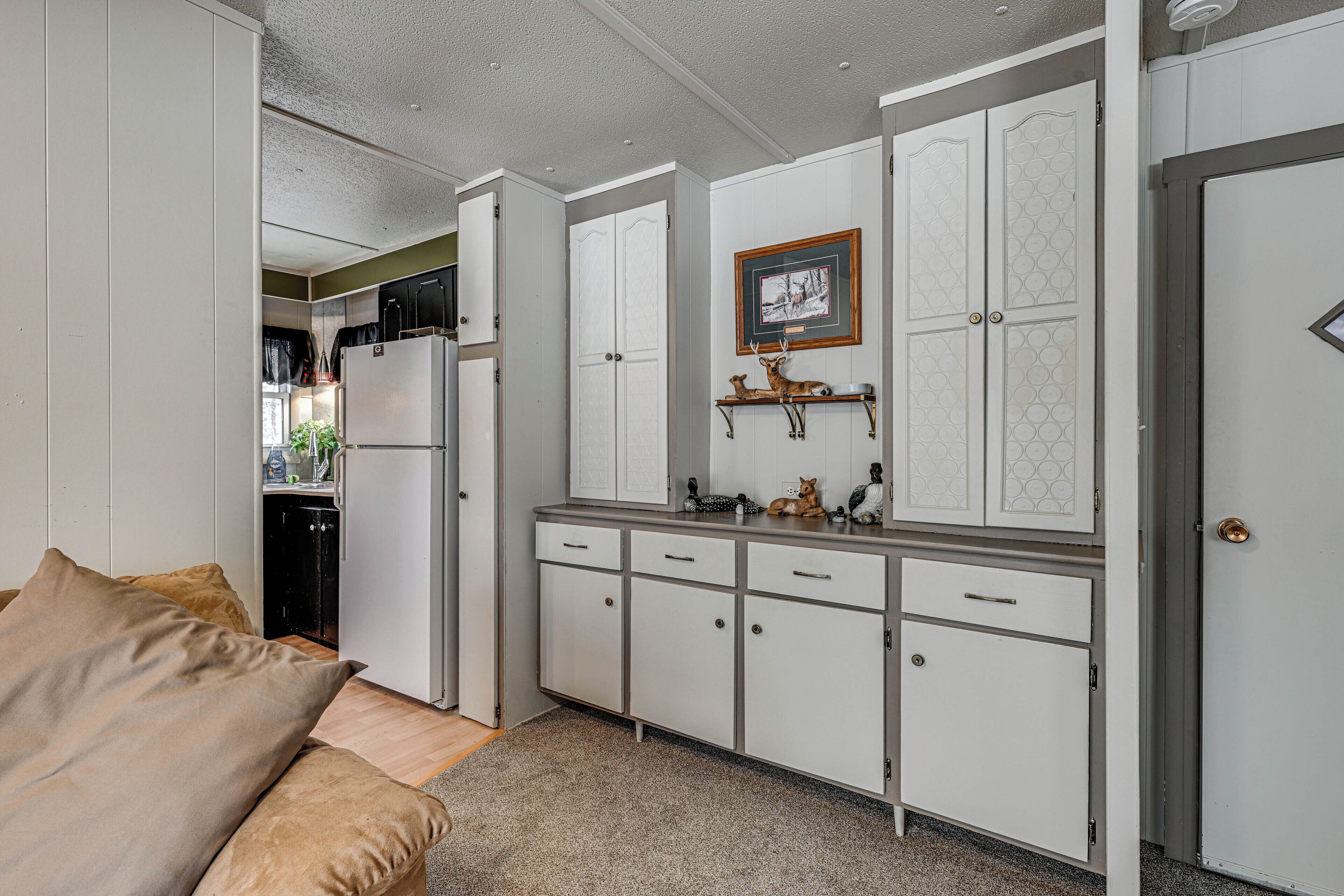 A compact kitchen with white cabinetry, a refrigerator, and a small countertop.