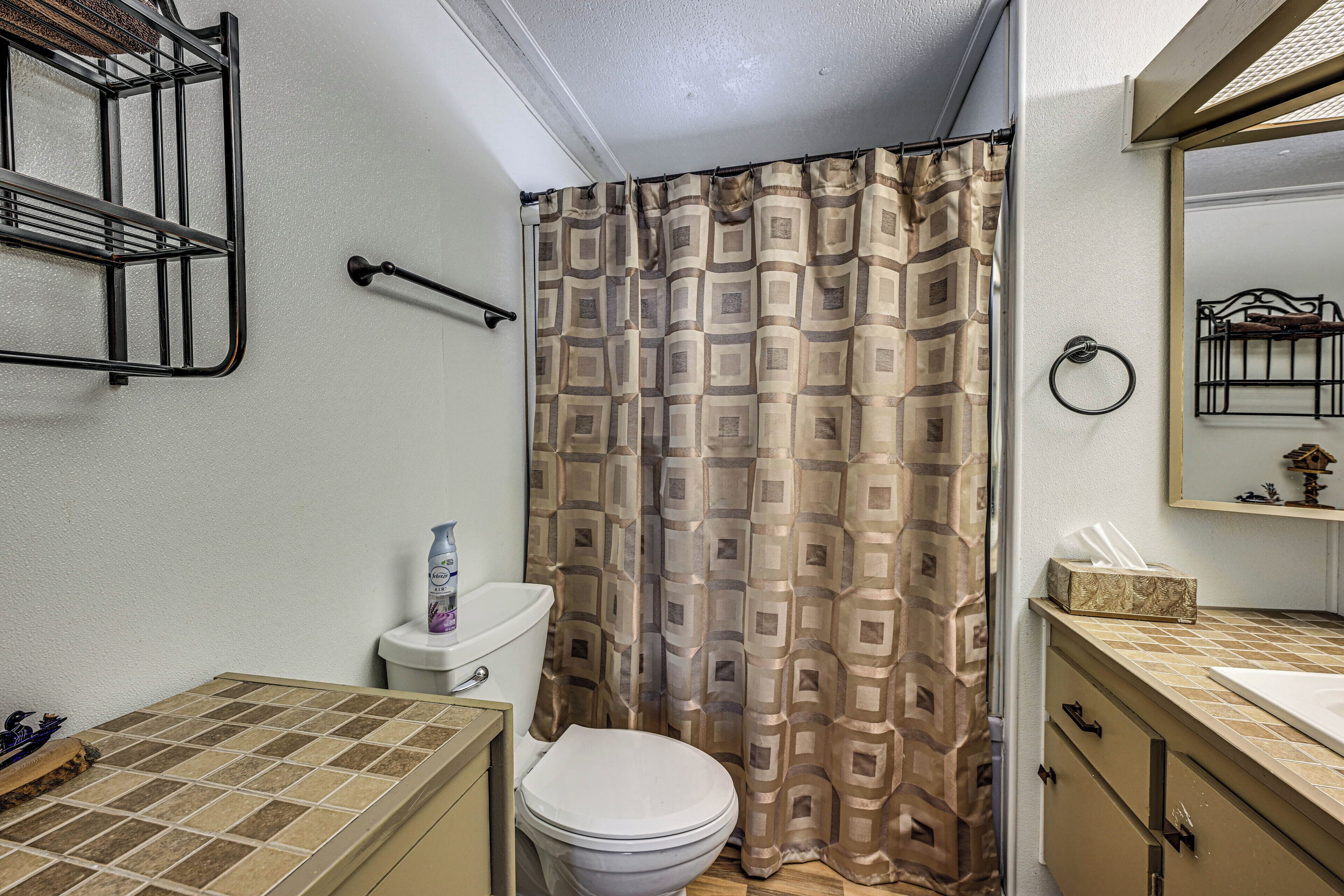 A bathroom with a toilet, a sink, a mirror, and a shower curtain.