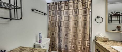 A bathroom with a toilet, a sink, a mirror, and a shower curtain.