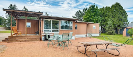 Une cabane dotée d’un porche couvert, d’un espace salon extérieur et d’une terrasse en gravier.