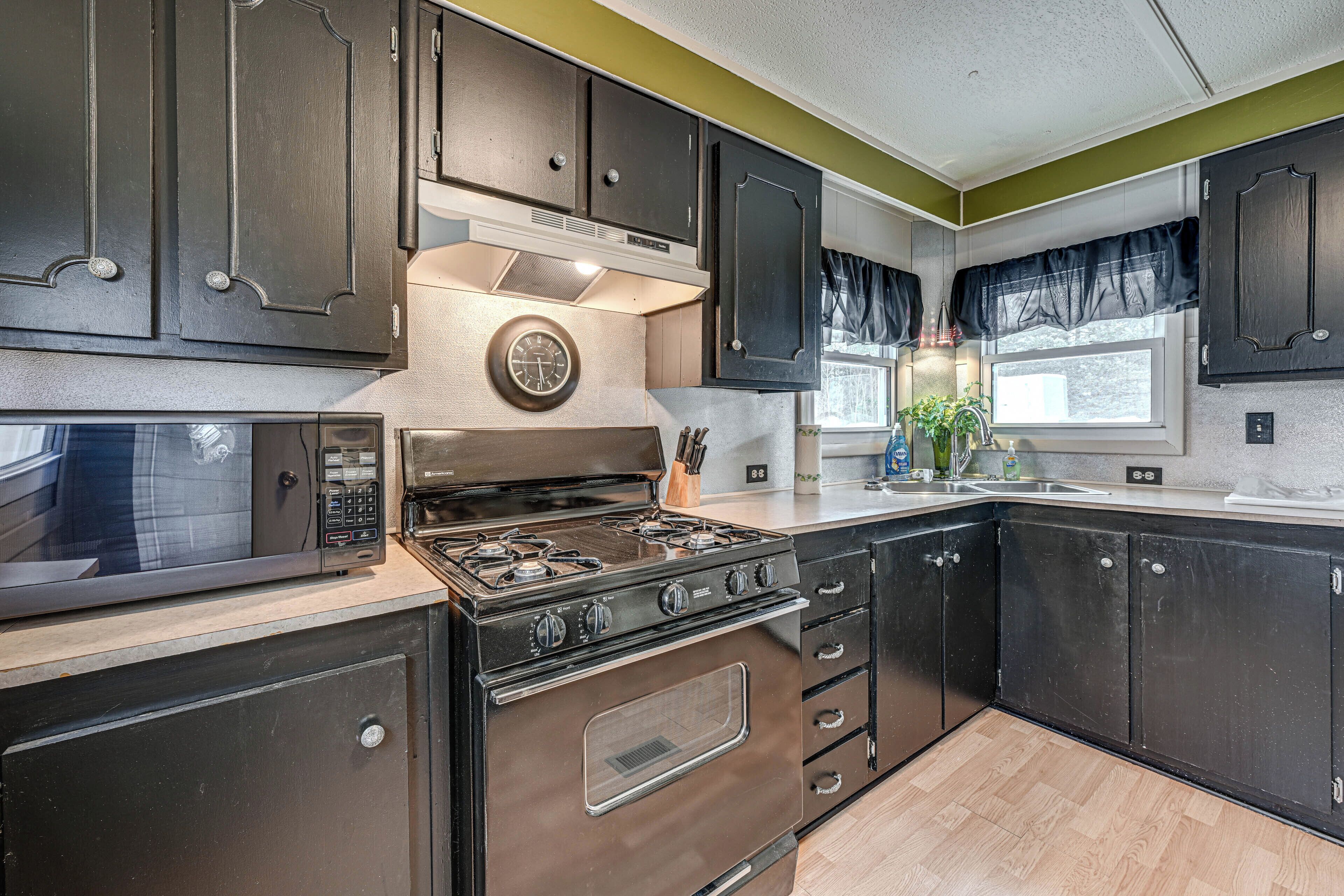A modern kitchen with dark cabinetry, a stainless steel stove, and a microwave.
