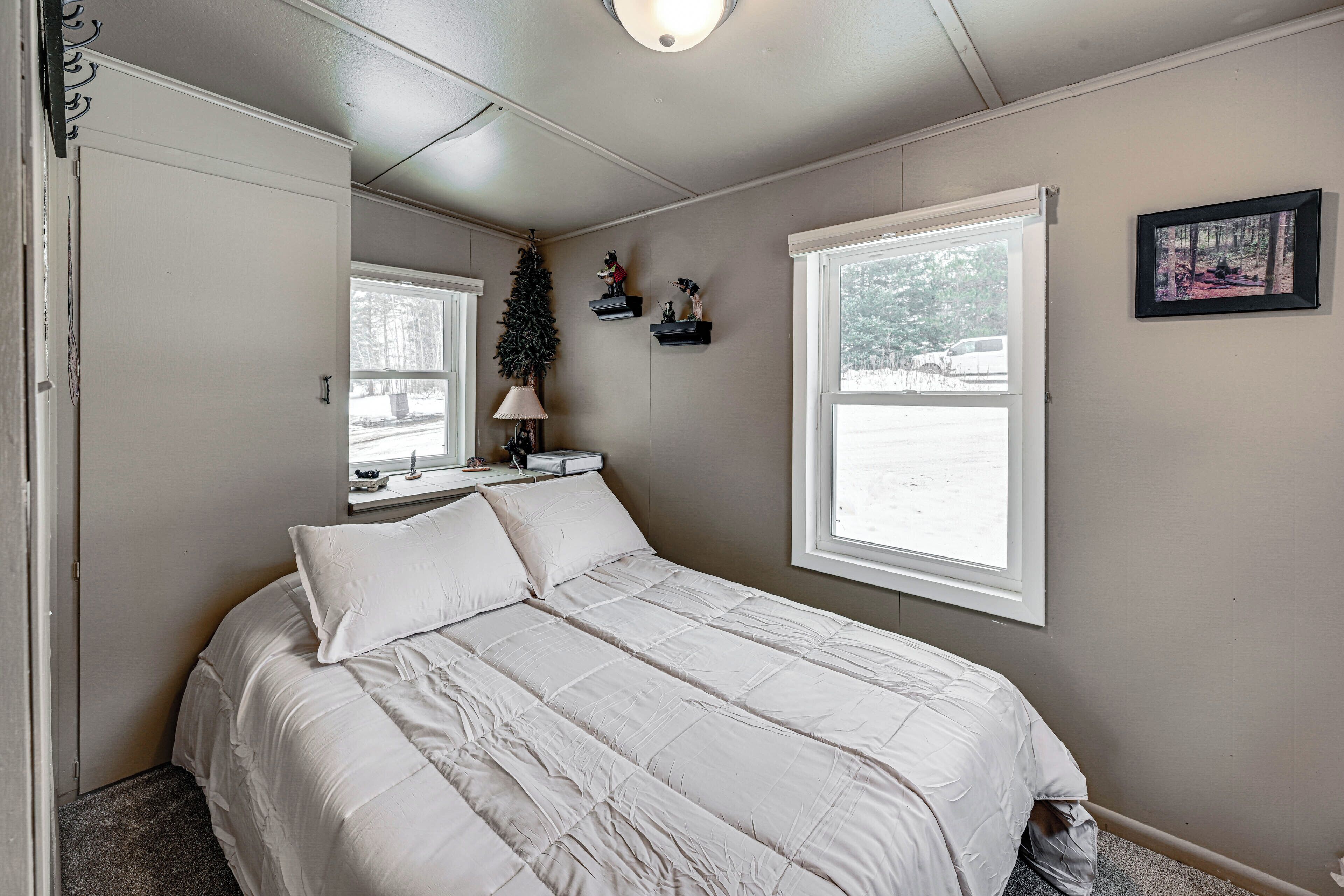 Un dormitorio con una cama grande, una ventana, un pequeño árbol de Navidad y un cuadro en la pared.
