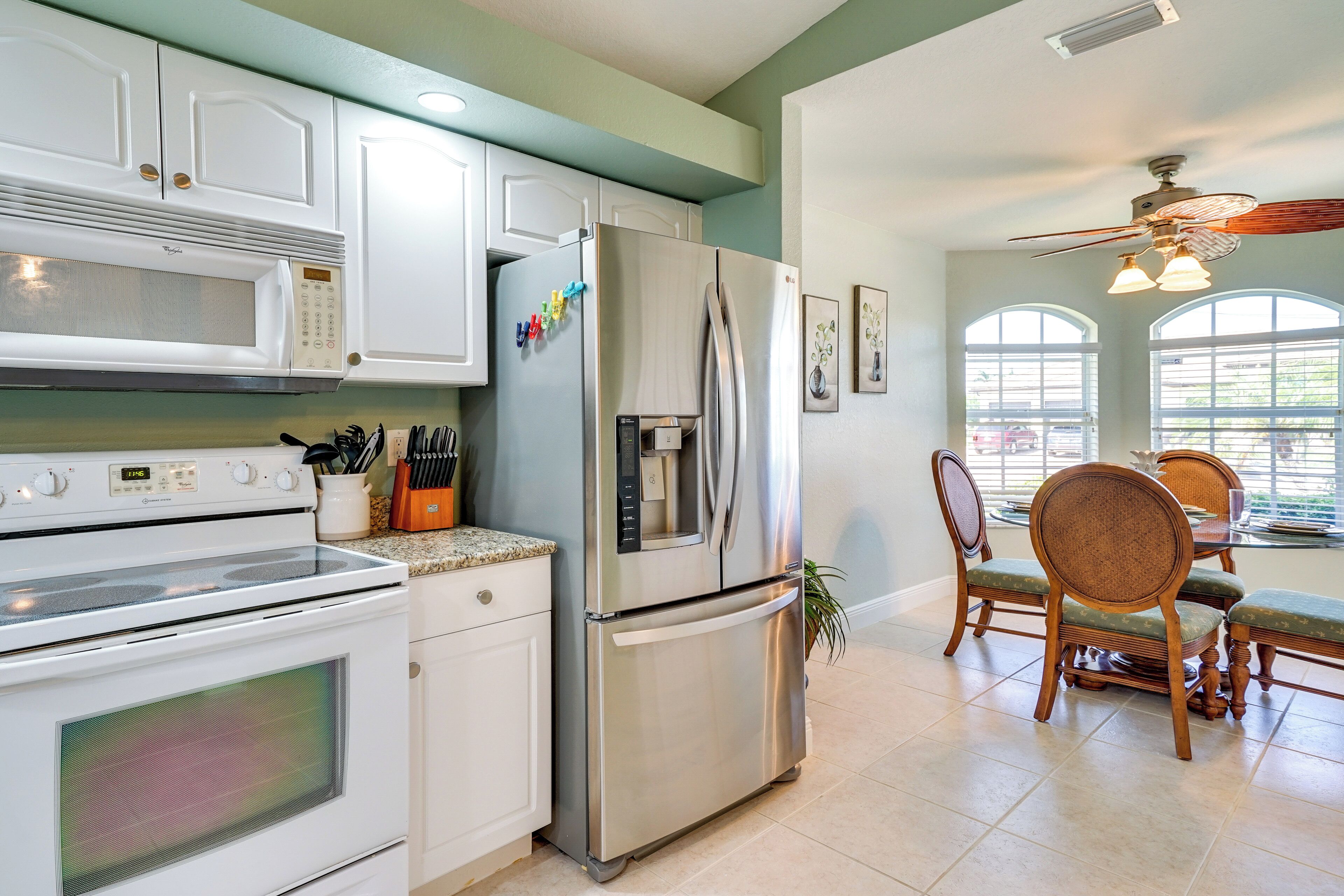A kitchen with white cabinets, stainless steel appliances, and a dining area with wooden chairs and a table.