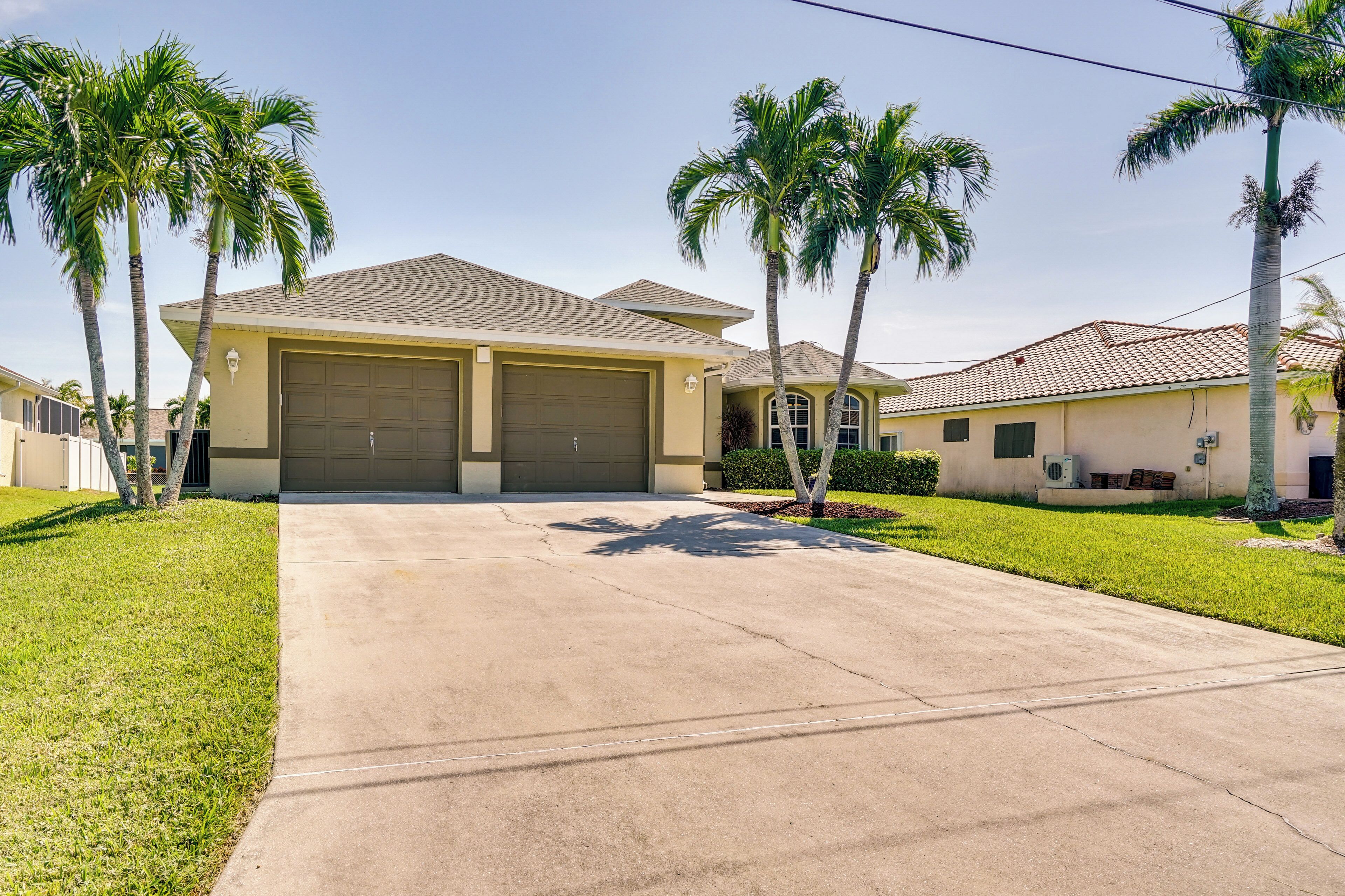 A residential house with a garage, two palm trees, and a well-maintained lawn.