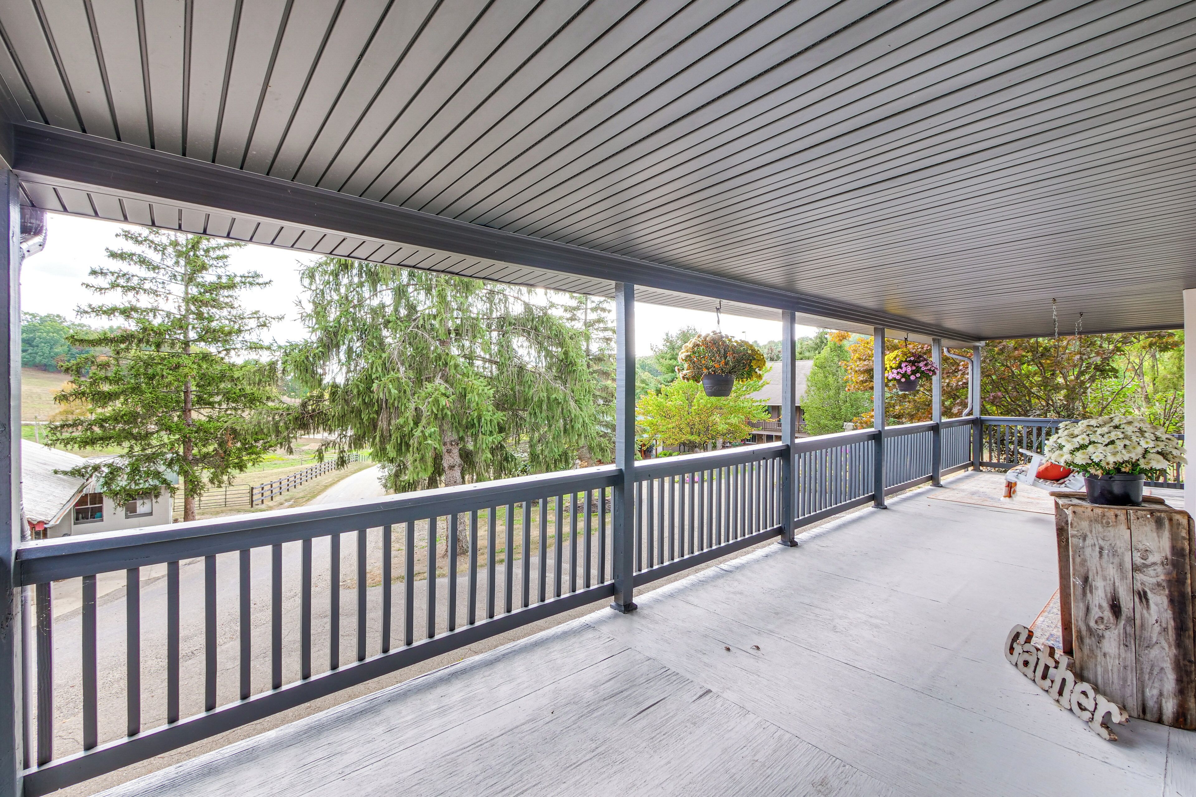 A covered porch with a railing, potted plants, and a 'Gather' sign.