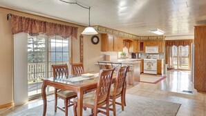 Una cocina amplia con armarios de madera, una isla central y un comedor con mesa de vidrio y sillas.
