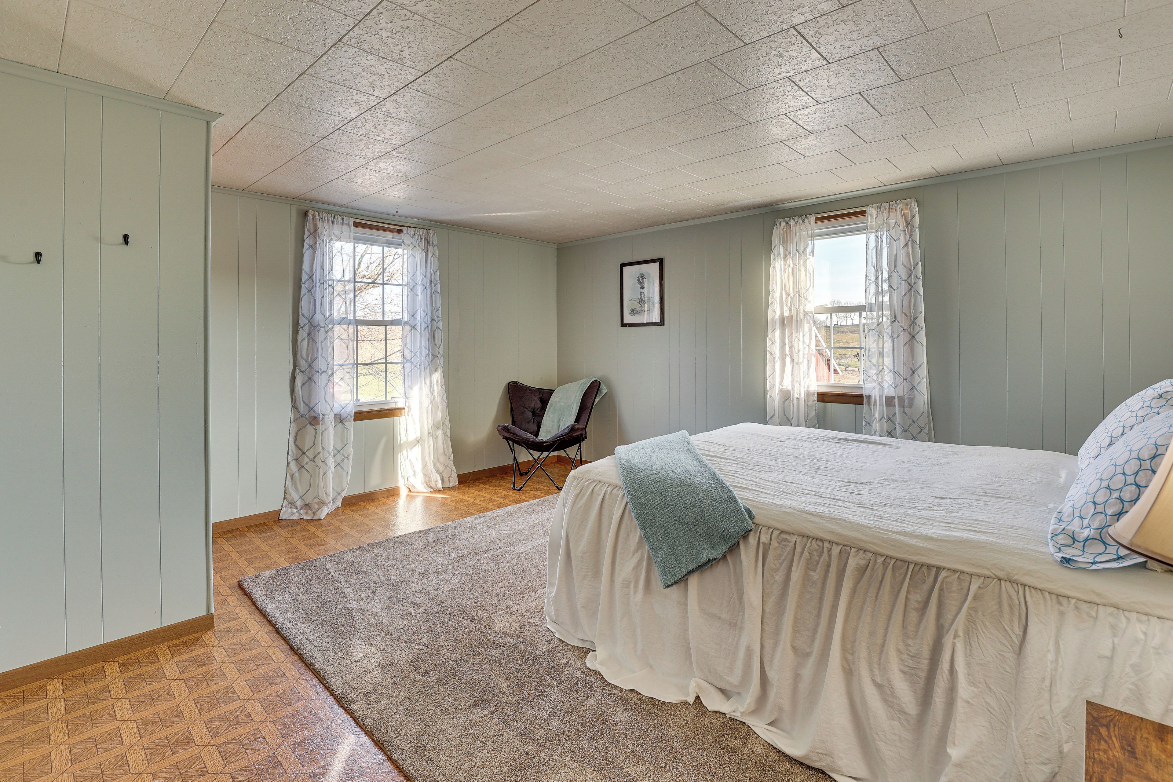 A bedroom with a large bed, a chair, and a window.