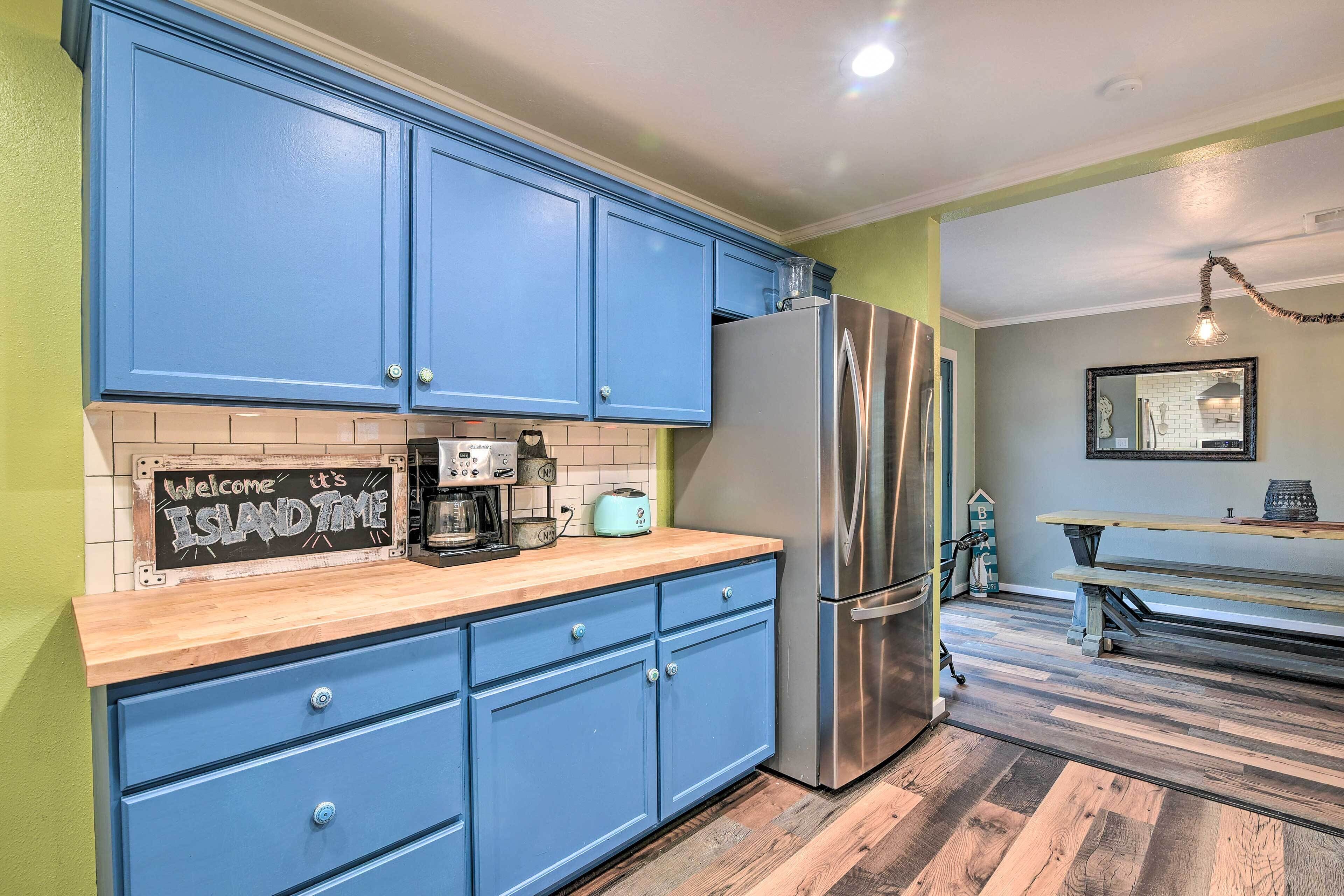 A kitchen with blue cabinets, a stainless steel refrigerator, and a wooden countertop.