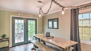 A room with a wooden table and benches, a sign reading "BEACH", and a view of the outdoors. - Galveston Group Getaway w/ Private Yard + Fire Pit (Galveston)