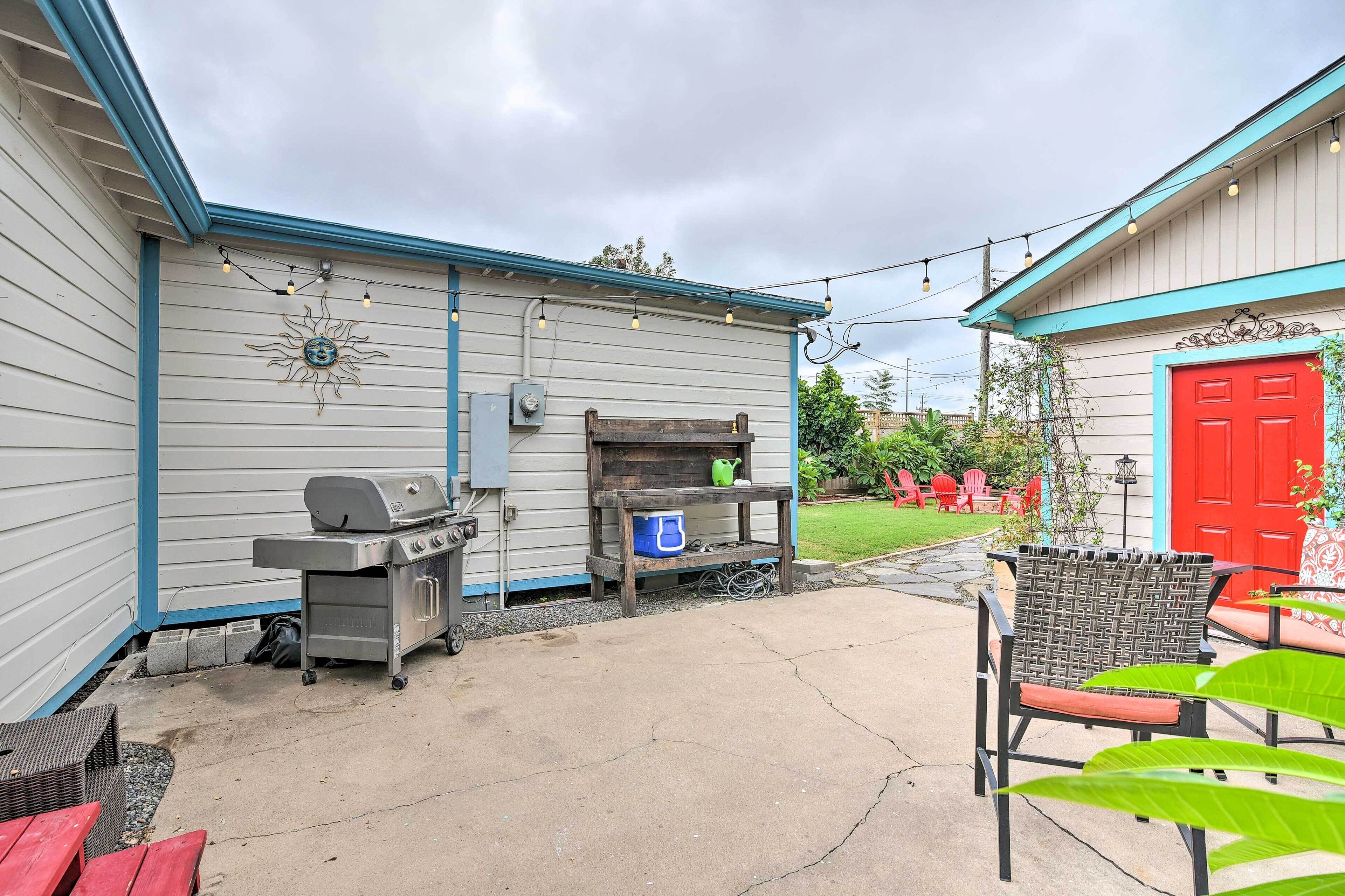 A patio with a grill, outdoor furniture, and a red door in the background.