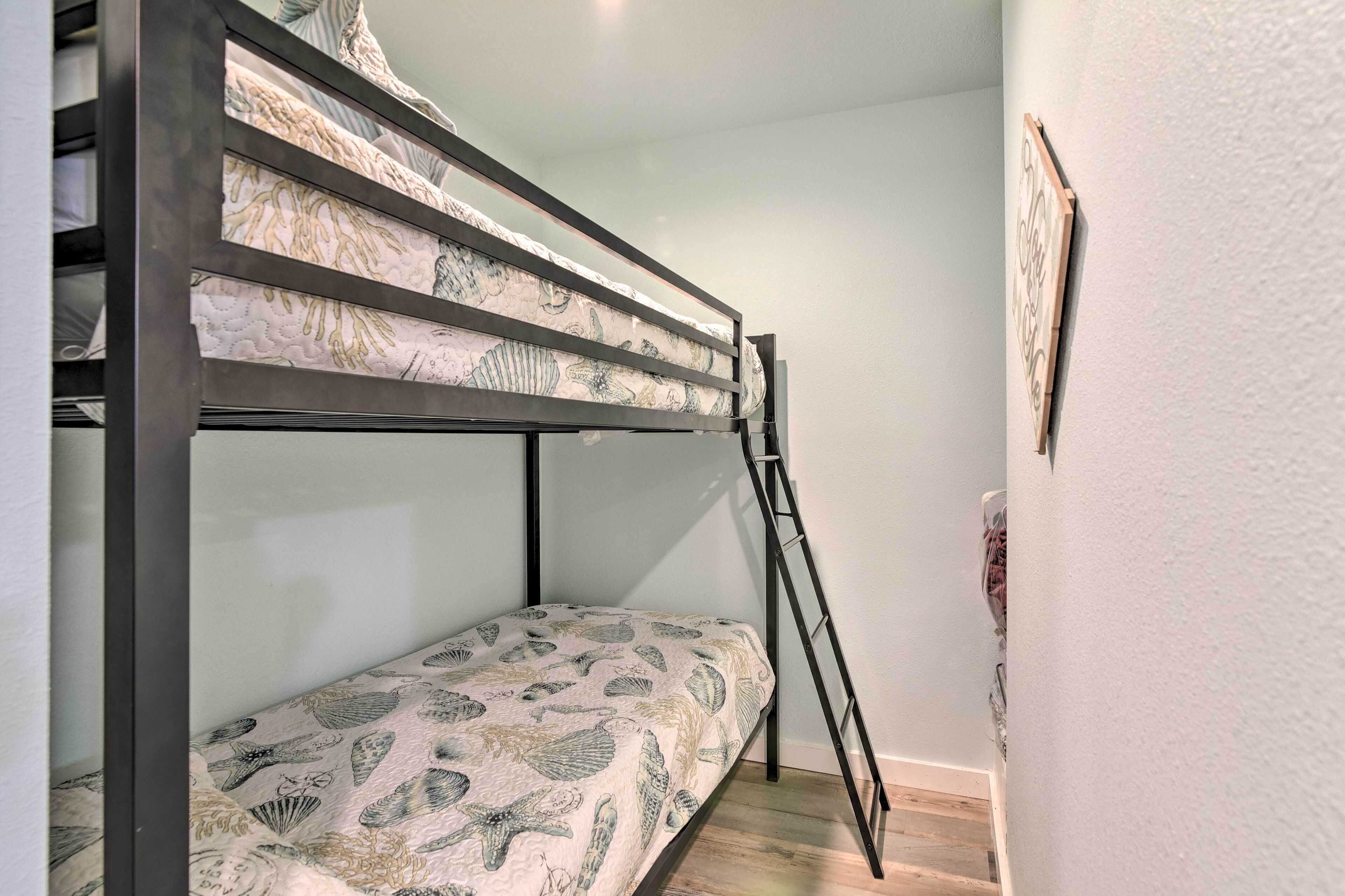 A bunk bed with patterned bedding, a ladder, and a framed picture on the wall.