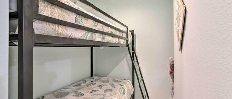 A bunk bed with patterned bedding, a ladder, and a framed picture on the wall.