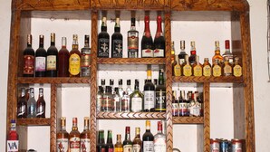 Un estante de madera con diferentes botellas de licor y latas.
