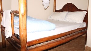 Una cama con dosel de madera, con ropa de cama blanca y un dosel colgante.