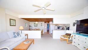 A compact living space with a sofa, a dining table, a TV, and a kitchenette. - Beachmark 4k 1 Bedroom Condo by RedAwning (Ocean City)