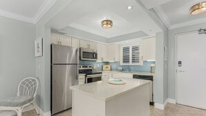 Una cocina moderna con armarios blancos, electrodomésticos de acero inoxidable y una isla central.