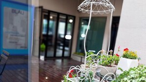 A wooden deck with a metal chair and table, surrounded by potted plants and a decorative metal umbrella. - BLAU mini hotel (Gyeongju)