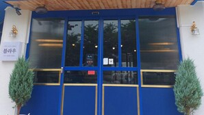 A hotel entrance with a blue facade, double doors, and two potted plants. - BLAU mini hotel (Gyeongju)