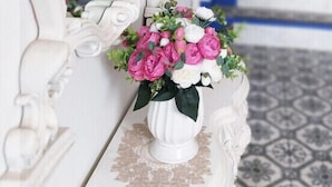 A white ornate mirror with a floral arrangement on a white table. A blue staircase is visible in the background. - BLAU mini hotel (Gyeongju)