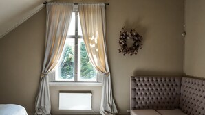A room with a large window, a grey upholstered sofa, and a white bed. - Topfloor apartment in historic villa - seaview (Vestland)