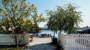 A patio area with a view of a lake, a white picket fence, and outdoor furniture. - Topfloor apartment in historic villa - seaview (Vestland)