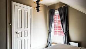 A bedroom with a white door, a bed, a window with curtains, and a ceiling light fixture. - Topfloor apartment in historic villa - seaview (Vestland)