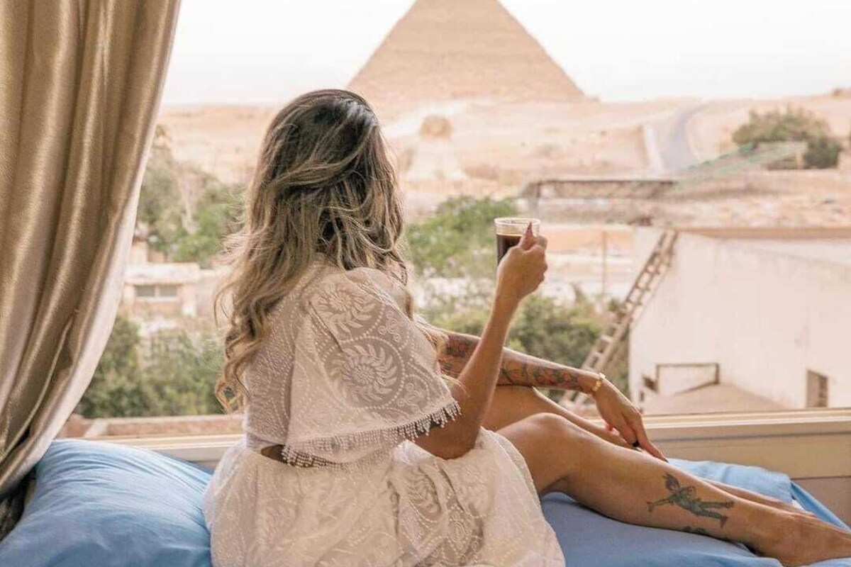 A person sitting on a bed with a view of a pyramid.