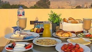Una mesa de desayuno con diversos alimentos y bebidas, con las pirámides de fondo.