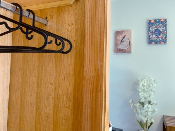 Una puerta de madera con un perchero de metal negro. Hay dos cuadros en la pared y un arreglo floral blanco.